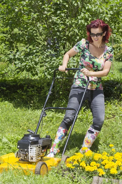 Smilling woman is mowing the grass — Stock Photo, Image