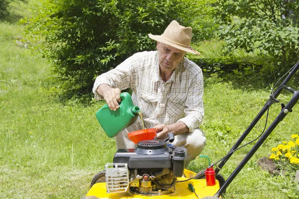 Midden leeftijd man olie aan lawnmover toe te voegen — Stockfoto