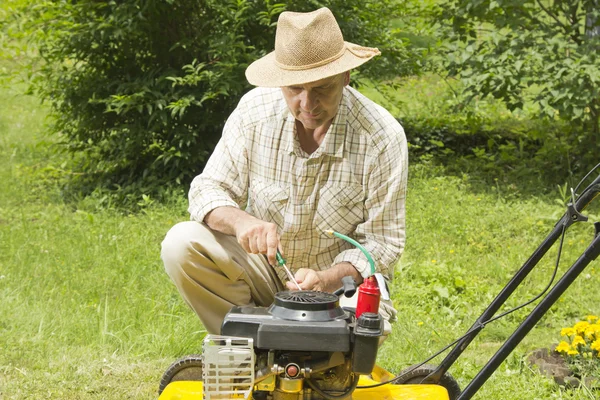 Мужчина средних лет ремонтирует газонокосилку — стоковое фото