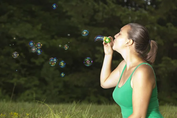 Linda chica soplando burbujas de colores — Foto de Stock