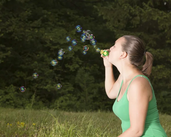 Linda chica soplando burbujas de colores —  Fotos de Stock