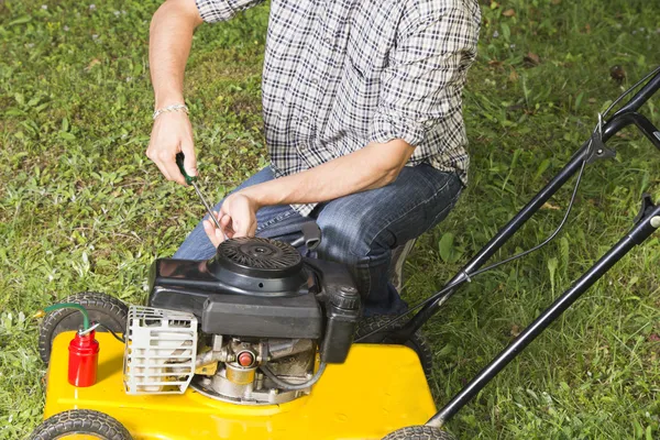 Homem reparando cortador de grama amarelo Close up — Fotografia de Stock