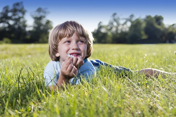 Kleine jongen liggen op het gras — Stockfoto