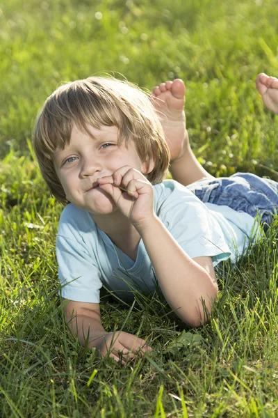 Jovem menino deitado na grama — Fotografia de Stock
