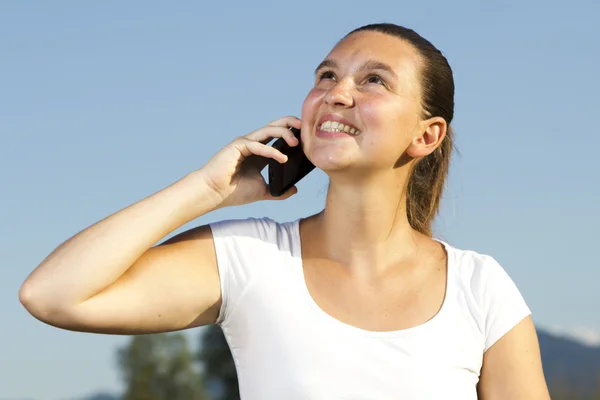Χαμογελώντας χαριτωμένο κορίτσι μιλάει στο τηλέφωνο δισκίο — Φωτογραφία Αρχείου