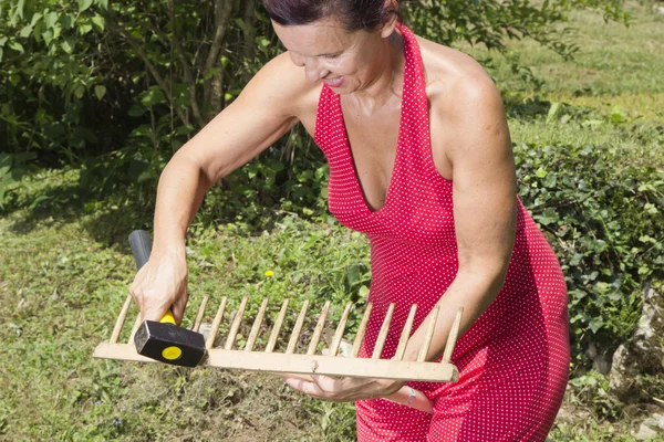Mujer reparando rake-closeup jardín de madera — Foto de Stock