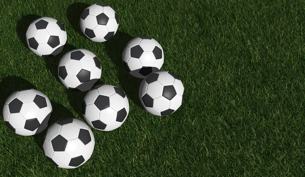 Футбольные мячи на зеленой траве — стоковое фото