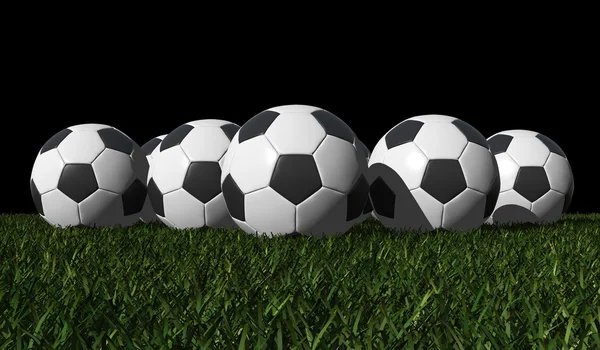 Футбольные мячи на зеленой траве — стоковое фото