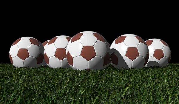 Brown soccer balls on a green grass — Stock Photo, Image