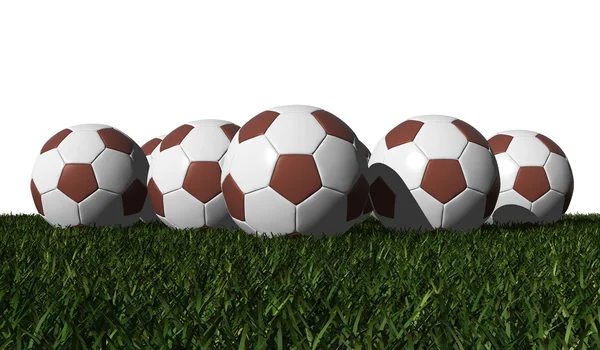 Brown soccer balls on a green grass — Stock Photo, Image