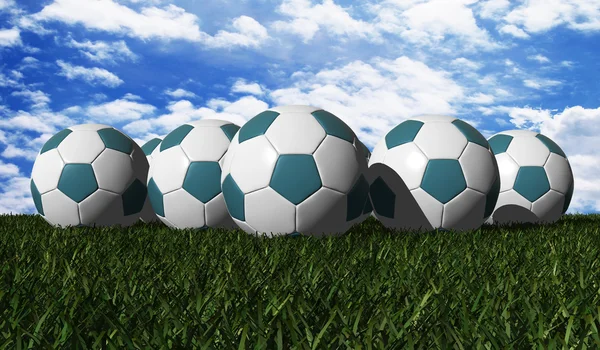 Cyan soccer balls on a green grass — Stock Photo, Image