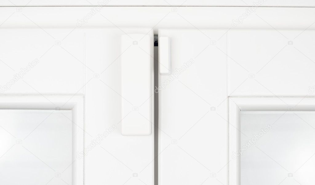 Wireless alarm sensor for window and door on white wooden sash