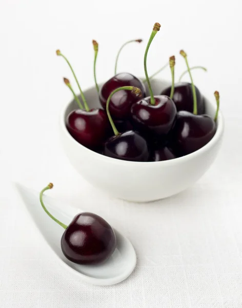 Cherry on white china spoon, cherries group in a white bowl — Stock Photo, Image