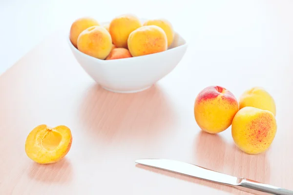 Abricots frais et un couteau de table sur fond de cuisine en bois — Photo