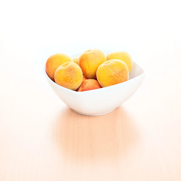 Fresh Apricots in white bowl on kitchen wooden background — Stock Photo, Image