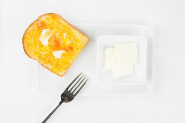 French toast, orange marmalade, butter, fork on white tablecloth clipart