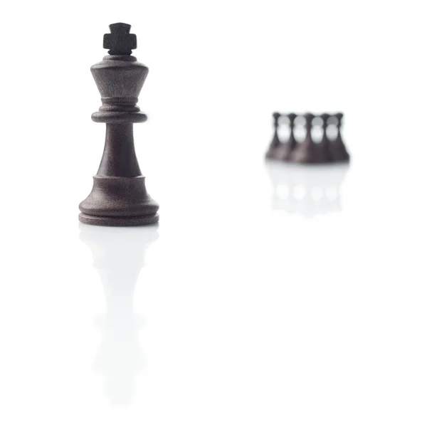 Шахматы. Черный король, пешки и их тени на белом фоне — стоковое фото