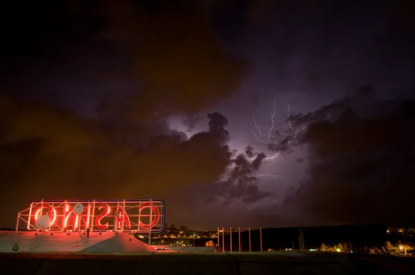 Ominous sky with thunderstorm and lightning above neon casino sign — Stock Photo, Image