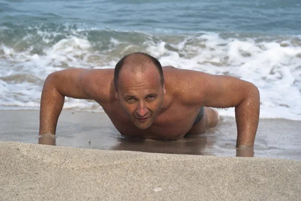 Jonge man doen pushups op het strand — Stockfoto