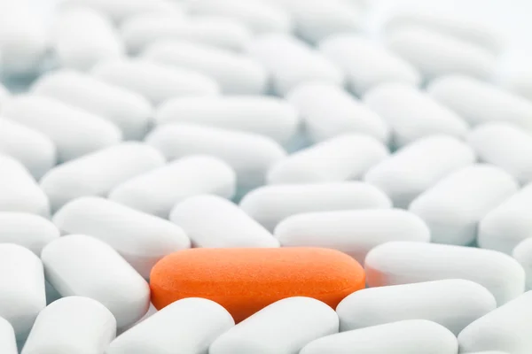 Индивидуальность - Оранжевая таблетка между белыми — стоковое фото