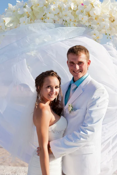 Bruden och brudgummen kramas framför arch — Stockfoto