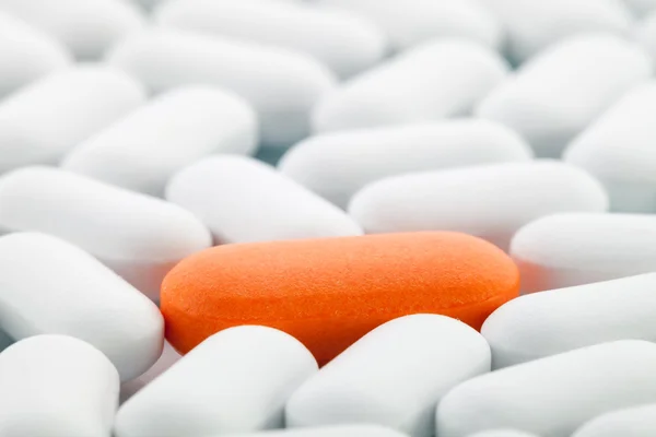 Pilule orange entre les blanches — Photo