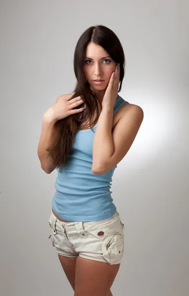 Una hermosa chica en una camiseta azul con un fondo gris . — Foto de Stock