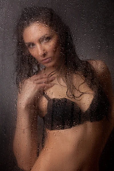 Chica en un sujetador negro y jeans para vidrio húmedo . — Foto de Stock