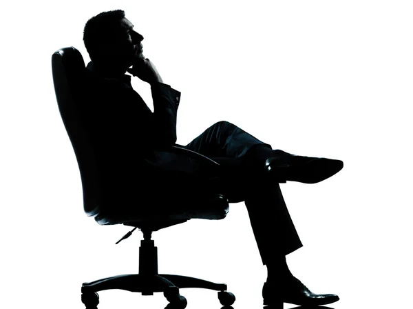 Um homem de negócios sentado em poltrona relaxante pensando silhueta — Fotografia de Stock