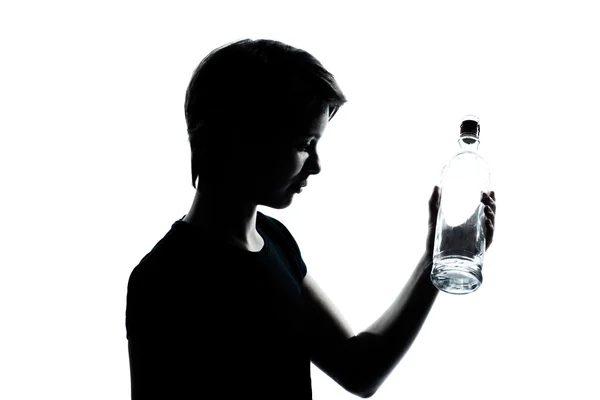 Un caucásico joven adolescente silueta niño o niña retrato sosteniendo vacío vodka botella de alcohol en estudio cortado aislado sobre fondo blanco — Foto de Stock