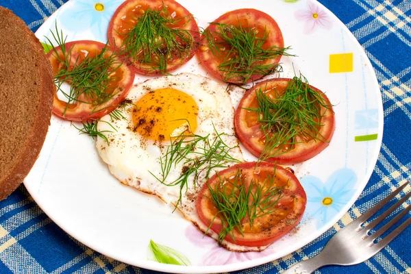 Assiette avec oeuf frit et tomates sur la nappe — Photo