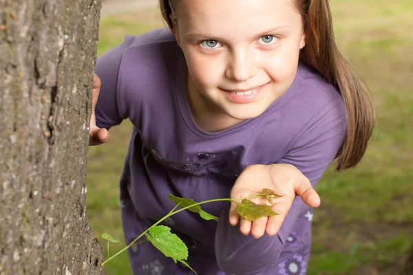Girl shows green shoot of tree — Stock Photo, Image