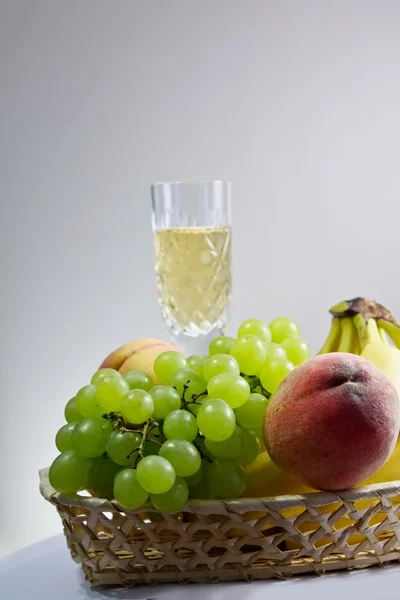 Broskve a hrozny se sklenkou vína — Stock fotografie