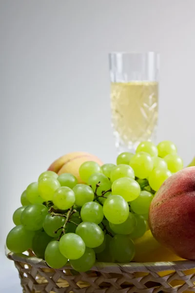 Perziken en druiven met een glas wijn — Stockfoto