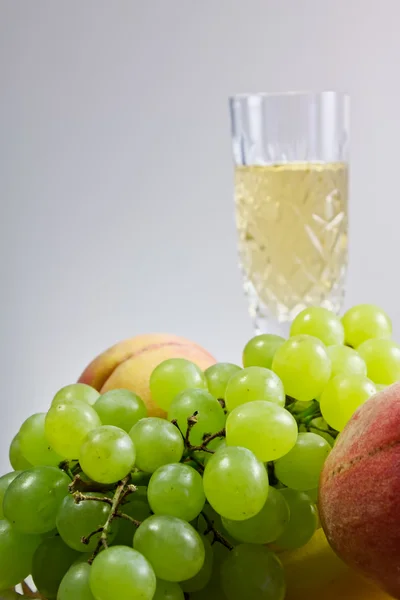 Melocotones y uvas con una copa de vino — Foto de Stock
