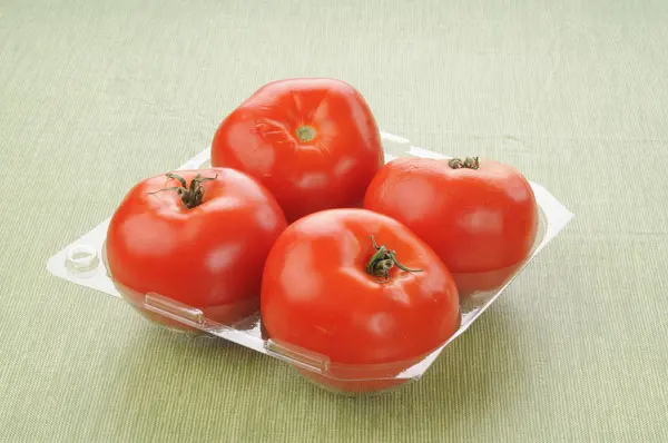 4 つのトマトとプラスチック製の容器 — ストック写真