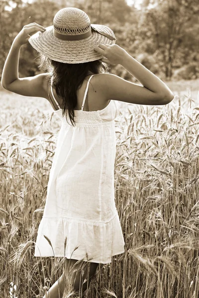 Young girl with hay hat in a wheat field — Stock Photo, Image