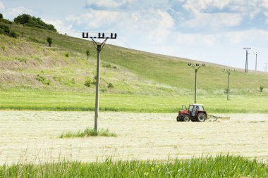 Tractor in a field - agricultural scene in summer clipart
