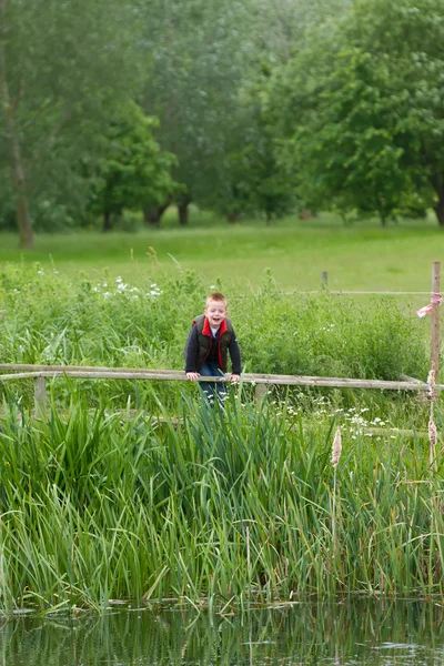 Mladý chlapec hraje v polích — Stock fotografie