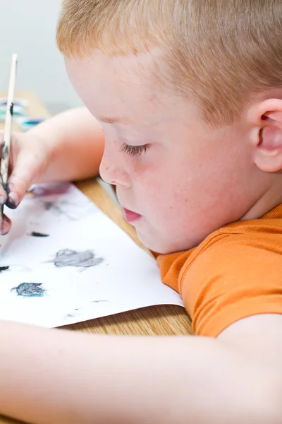 Pieni poika maalaamassa kuvaa — kuvapankkivalokuva