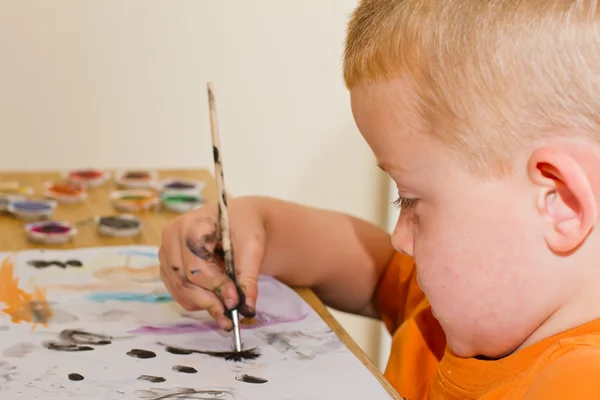 Pieni poika maalaamassa kuvaa — kuvapankkivalokuva