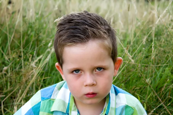 Sad boy scowling whilst looking ahead — Stock Photo, Image