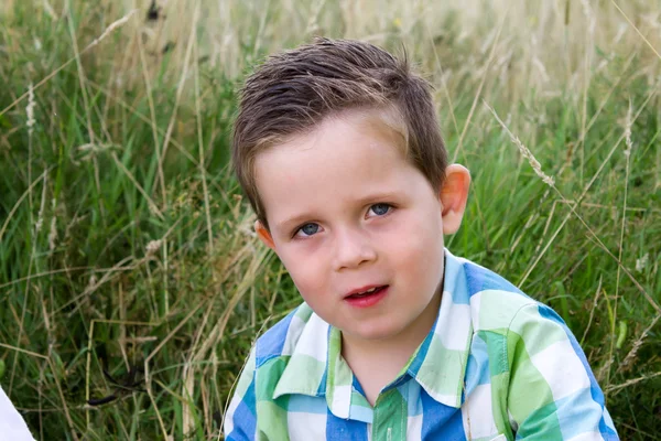 Usmíval se šťastný chlapec v travnaté hřiště — Stock fotografie