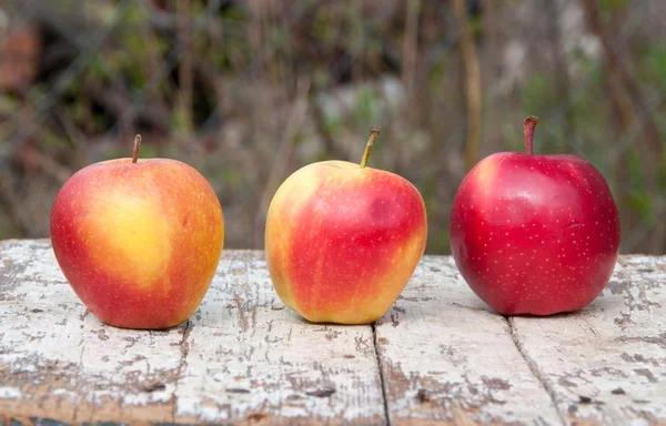 Three red apples on a wooden table — Stock Photo, Image