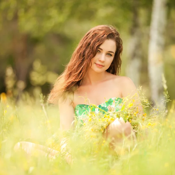 Jonge redhead vrouw in het park met bloemen — Stockfoto