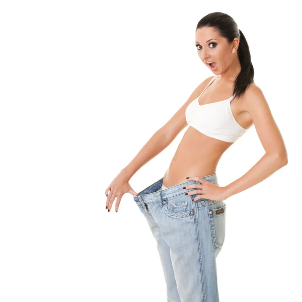 Pretty woman shows her weight loss by wearing an old jeans — Stock Photo, Image