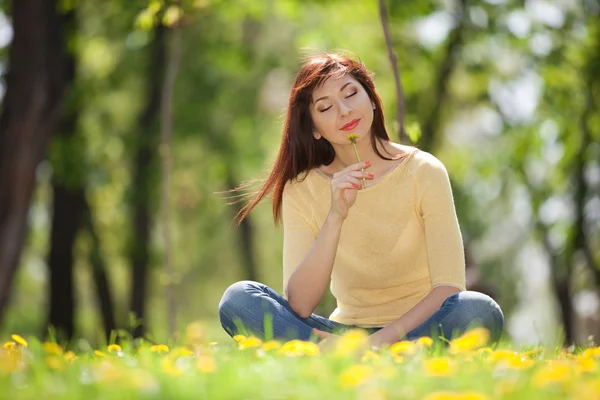 Junge rothaarige Frau im Park mit Blumen — Stockfoto