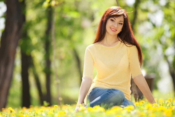 Молодая рыжая женщина в парке с цветами — стоковое фото