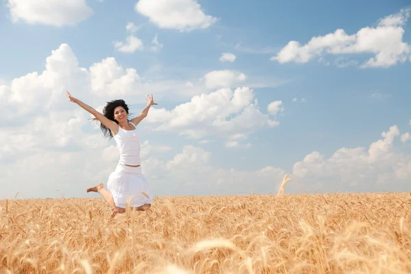 Happy woman jumping in golden wheat — Stock Photo, Image