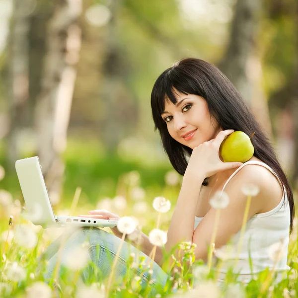 민들레와 함께 공원에서 흰색 노트북으로 귀여운 여자 — 스톡 사진